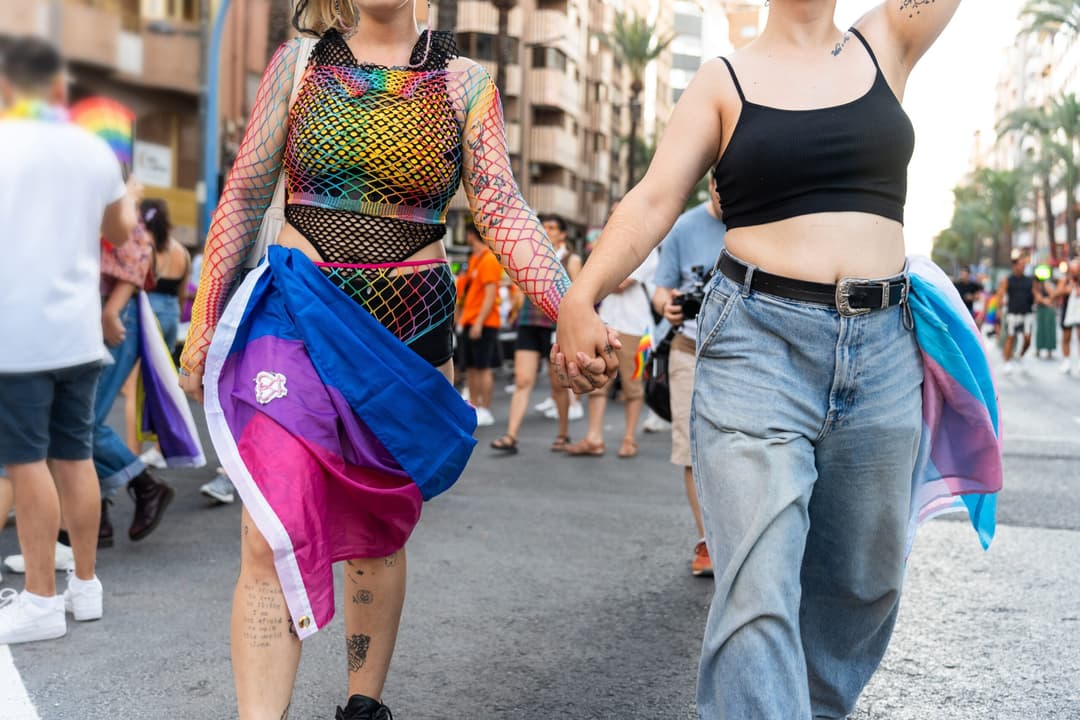 Two,Women,Are,Holding,Hands,And,Walking,Down,The,Street
